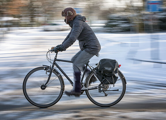 Mann fährt auf ungeräumten Radweg im Winter